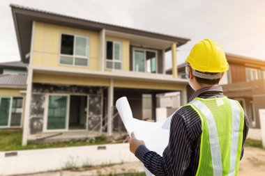 İnşaat alanındaki koruma miğferi ve bina planlarında uzman mühendis.