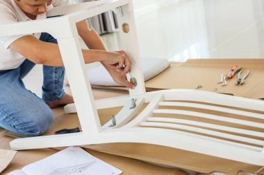 Beyaz koltuk mobilyalarını evde monte eden adam.