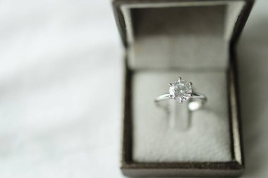 Beyaz kumaş arka planında mücevher hediye kutusu olan elmas yüzük.