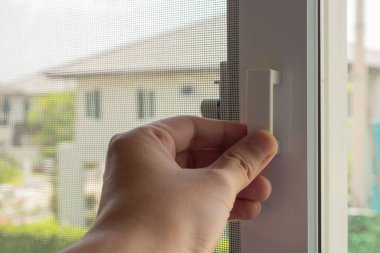 Ev penceresinde el ele tutuşan sivrisinek ağı tel ekran sapı