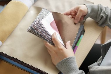 Kumaş rengi örnekleri olan kadın tasarımcı perde için tekstil seçiyor