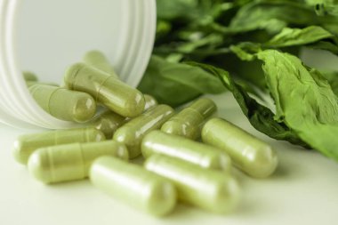 Andrographis 'in beyaz arka planda paniklediği bitkisel ilaç kapsülleri