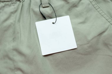 Gri kumaş doku arka planında boş beyaz kıyafet etiketi