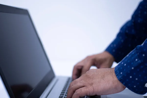 Closeup, People work home blogger. A man standing and typing with a keyboard notebook computer on a white desk in the living room at home. The screen is a blank, White blurred background, Copy space