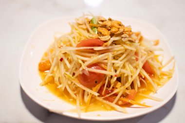 Papaya salatasında biber, kurutulmuş karides ve domates yerel ve baharatlı olması için Tayland yemeğidir. Tabak beyazı, masa fotoğrafçılığı raptiyesi yakın plan, manzara ve yenilebilir..