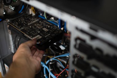 Tamir için grafik kartını bir teknisyen tutuyor. VGA kartı hasar gördü ve bilgisayarın çökmesine neden oldu. Ekran kartı kişisel bilgisayar ekranı göstermez. Yakından çek. Bulanık arkaplan