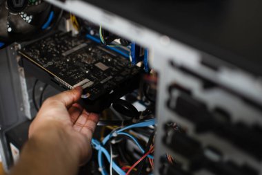 Tamir etmek için bir teknisyenin elinde grafik kartı var. VGA kartı hasar gördü ve bilgisayarın çökmesine neden oldu. Ekran kartı bir PC ekranı göstermiyor. Fotoğrafı kapat ve seçici odaklan..