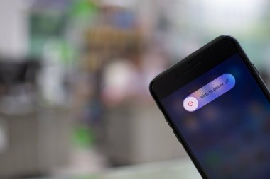 Songkhla, Hatyai, Tayland 5 Kasım 2020: Elle tutulan Apple iPhone 7 artı ekranda güç kapama seçeneği olan bir ofiste siyah renk, yakın çekim fotoğrafçılık, bulanık arkaplan çok güzel