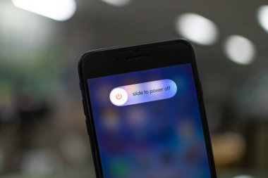 Songkhla, Hatyai, Tayland 5 Kasım 2020: Elle tutulan Apple iPhone 7 artı ekranda güç kapama seçeneği olan bir ofiste siyah renk, yakın çekim fotoğrafçılık, bulanık arkaplan çok güzel