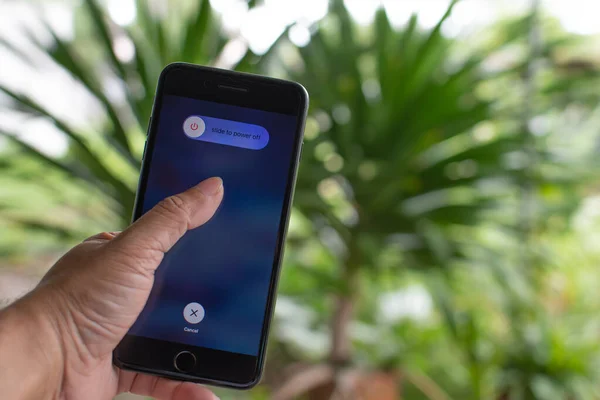 Phuket, Phi Phi, Tayland 8 Ekim 2020: Elle tutulan Apple iPhone 7 artı ekranda güç kapama seçeneği, yakın çekim fotoğrafçılık ve arka plan bokeh güzel