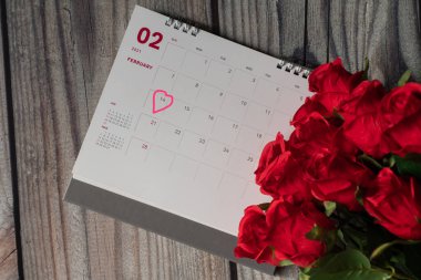 Üst manzara, sembol kalp işareti 14. gün pembe. 14 Şubat 2021 'deki Sevgililer Günü konsepti, beyaz masanın üzerinde bulanık gül çiçeği olan Şubat takvimi. Yakın çekim ve seçici odaklanma.