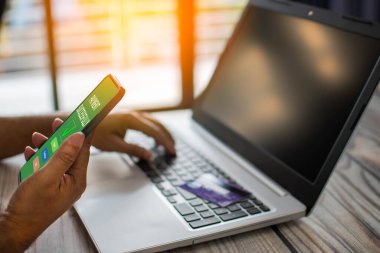 Erkekler internetten alışveriş yapmak için akıllı telefon kullanır. İş adamları internet üzerinden para transfer ediyorlar. Ödemek için akıllı telefon tutan bir adam. İş adamları masa başında dizüstü bilgisayar kullanır. Seçici odaklanma. Arka plan bulanık. Akıllı telefon bir ödeme ekranı görüntüler