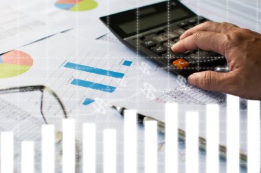 Finansal işlem numaralarını hesaplamak için adamın parmağı bir hesap makinesine basar kalem, kağıt üzerinde gözlük, mali istatistikleri gösteren grafikler, yakın plan, bulanık arkaplan...