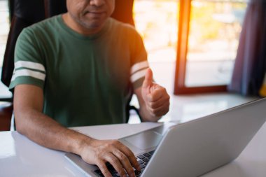 Bir adam internetle iletişim kurmak için dizüstü bilgisayar kullanıyor. Defter bilgisayarıyla internetten serbest öğrenim. COVID-19 salgını sırasında iş adamları evde çalışıyor. Seçici odaklanma. Bulanık arkaplan