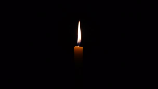 一支蜡烛的光芒在微风中摇曳着 在黑暗中被美丽地照耀着 在宗教仪式上点燃一支金色的蜡烛 在仪式中使用蜡烛的概念 — 图库视频影像