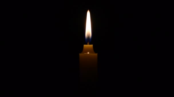 一支蜡烛的光芒在微风中摇曳着 在黑暗中被美丽地照耀着 在宗教仪式上点燃一支金色的蜡烛 在仪式中使用蜡烛的概念 — 图库视频影像