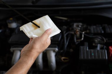 Motor bakımı kavramı. Bir teknisyen motor yağının seviyesini kontrol ediyor. Motor yağını silmek için beyaz mendil tutan adam. Kapat, bulanık arkaplan