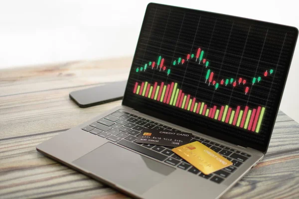 The graph displayed on a laptop screen and a credit card placed on the keyboard. Concept for trading stocks using credit cards and, online, rate, business, finance, selective focus, white background