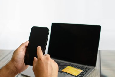 Erkekler internetten alışveriş yapmak için akıllı telefon kullanır. İş adamları internet üzerinden para transfer ediyorlar. Ödemek için akıllı telefon tutan bir adam. İş adamları masa başında dizüstü bilgisayar kullanır. Seçici odaklanma. Bulanık arkaplan.