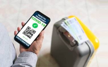 Koronavirüs ya da COVID-19 aşısı aşısını göstermek için elinde akıllı telefon olan turistler. Koronavirüsün yayılmasını önlemek için. ve aşıdan sonra güvenlik gösterileri.