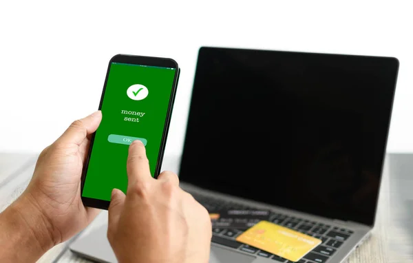Bir adamın eli ekranda akıllı telefonu tutar para gönderilir ve bir tuşa basılır. Mobil cihazlarla yapılan finansal işlemler kavramı. Para, transfer, telefon, kopyalama alanı. Beyaz arka grup
