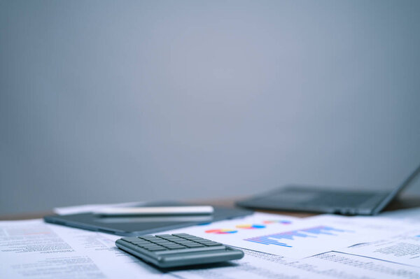 A professional workspace featuring a calculator positioned atop detailed financial reports and colorful data charts. This visual symbolizes diligent financial analysis and strategic business