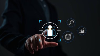 Bir el, stratejik planlamayı, veri analizini ve hedef alınan bağlantıyı vurgulayan, gelecekteki dijital arayüzle etkileşim halindedir. Simgeler, yenilikçi yaklaşımları vurgulayarak büyüme, araştırma ve hedefleri temsil ediyor