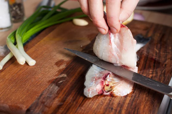 Proceso de cocción de pescado. Las manos cocinan cortan el pescado en una tabla de cortar de madera — Foto de Stock