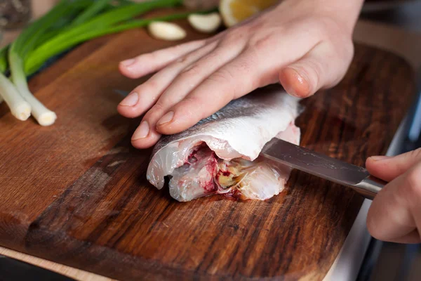 Процесс приготовления рыбы. Руки повара порезали рыбу на деревянной доске Стоковое Изображение