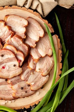 Tahta tabakta dilimlenmiş leziz domuz eti, yeşil soğanla servis edilir.