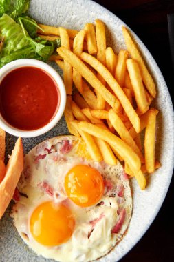 Büyük kahvaltı tabağı - domuz pastırmalı kızarmış yumurta, yeşil salata, patates kızartması, peynirli ekmek ve konfeksiyon ve domates sosu..