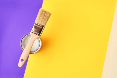 Parlak proton mor ve sarı arka planda beyaz boya ile olabilir yatıyor boyama fırça. Minimalizm, boşaltmak ile.