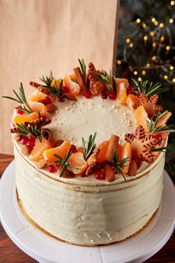 Turunçgil, badem, kızılcık ve biberiyeyle süslenmiş Noel pastası..