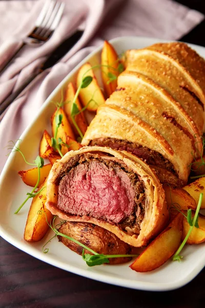 Delicious beef wellington served with baked potato and microgreens. Classic steak dish, great centerpiece on special occasion.