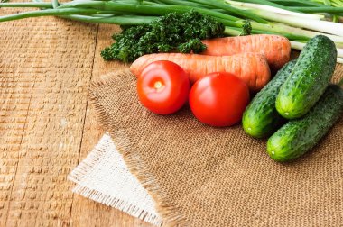 Ahşap masa üzerinde bir çuval bezi üzerinde taze sebze