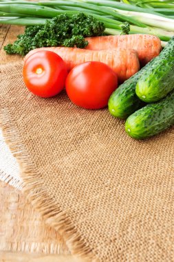 Ahşap masa üzerinde bir çuval bezi üzerinde taze sebze