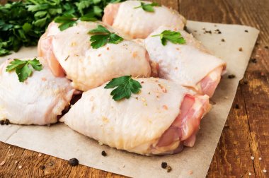 Raw chicken thighs with parsley on wooden table clipart