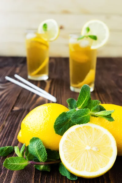 Lemons with mint and two glasses of ice tea on wooden table — Stock Photo, Image