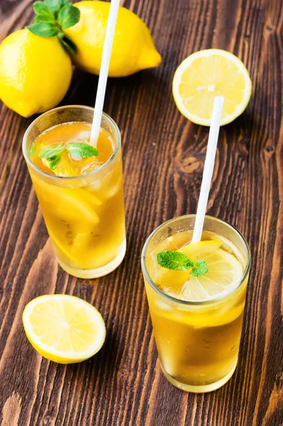Two glasses of ice tea with ice-cubes on wooden table — Stock Photo, Image