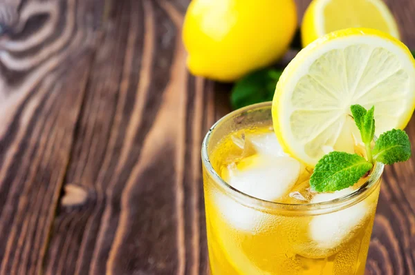 Glass of ice tea with lemons on wooden table — Stock Photo, Image