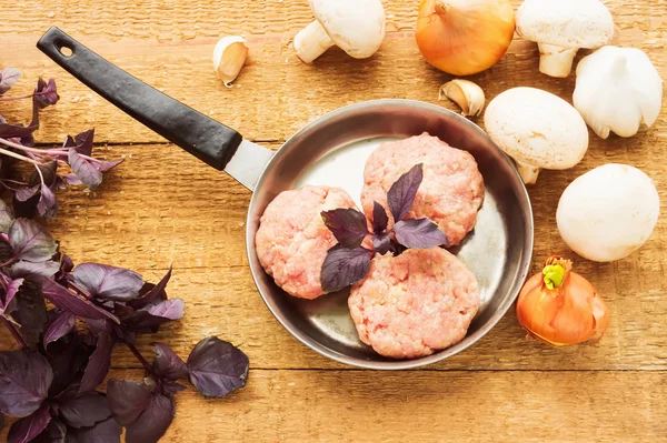 Свежее сырое мясо с базиликом на сковороде, на деревянной спине — стоковое фото