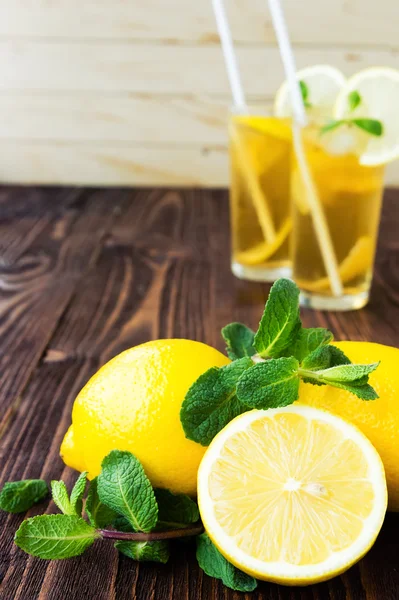 Lemons with mint and two glasses of ice tea on wooden table — Stock Photo, Image