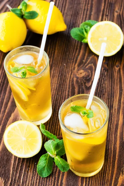 Two glasses of ice tea with ice-cubes on wooden table — Stock Photo, Image