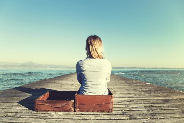 Mujer relajada sentada en su gran maleta después de un largo viaje — Foto de Stock