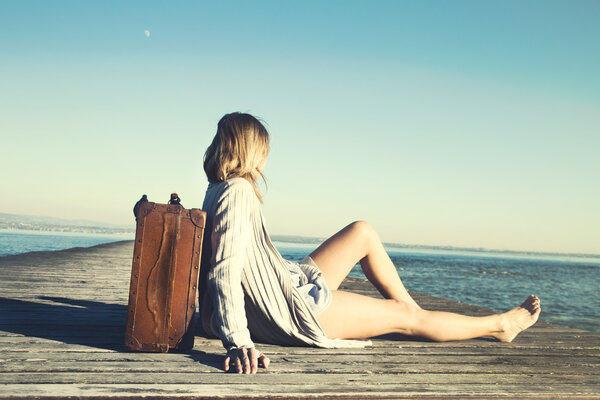 расслабленная женщина отдыхает после долгого путешествия со своим большим чемоданом
