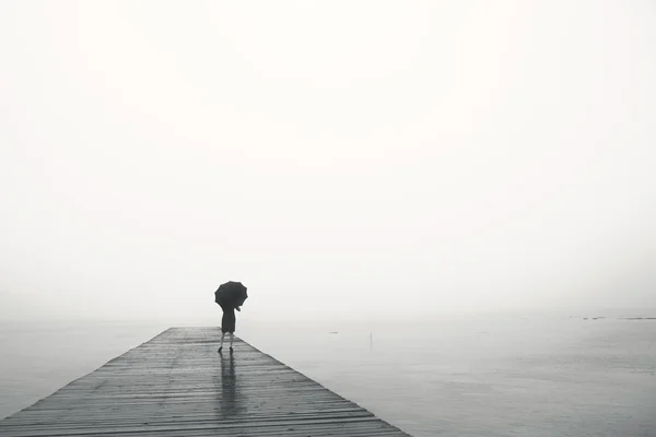 Woman with umbrella contemplates peacefully in front of a sea — Stock Photo, Image