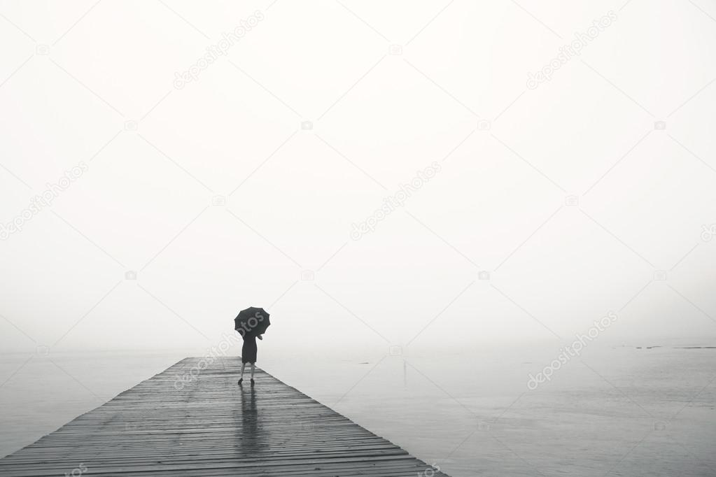 woman with umbrella contemplates peacefully in front of a sea