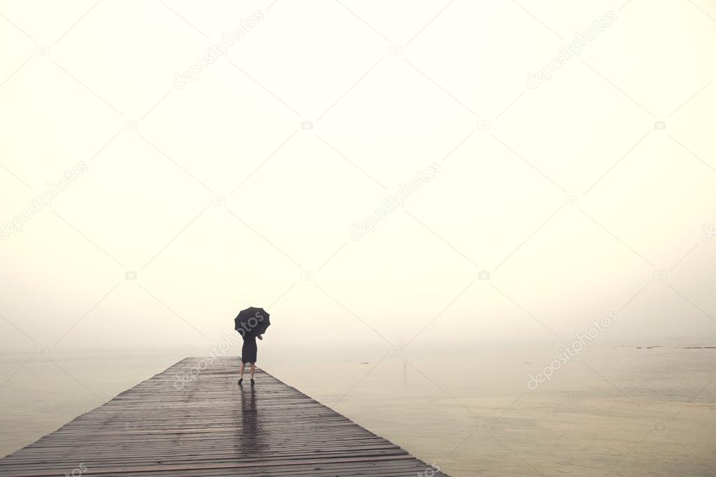 woman with umbrella contemplates peacefully in front of a sea