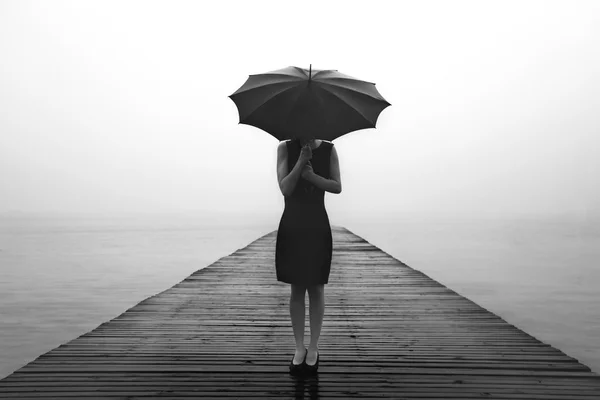 Mulher com guarda-chuva preto olhando infinito em um lugar surreal — Fotografia de Stock