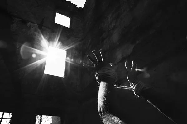 Заключенная женщина протягивает руки к свету в знак надежды — стоковое фото